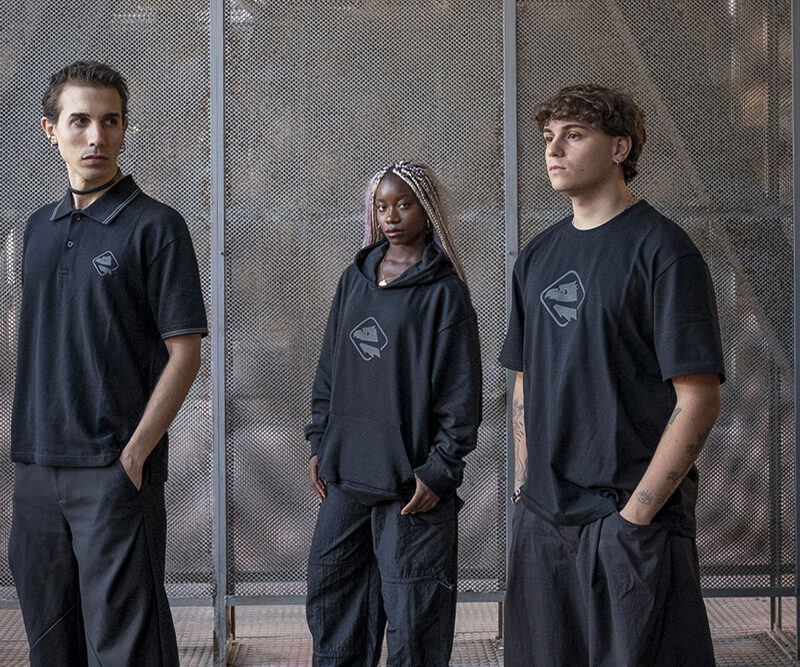 Tre persone indossano polo, felpa e t-shirt nere della Black Collection Palermo FC in un ambiente industriale con strutture metalliche